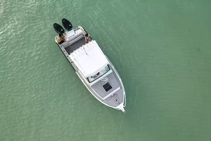 Aerial view of a white fishing boat navigating the calm, turquoise waters of Seychelles, ideal for a fishing tour.