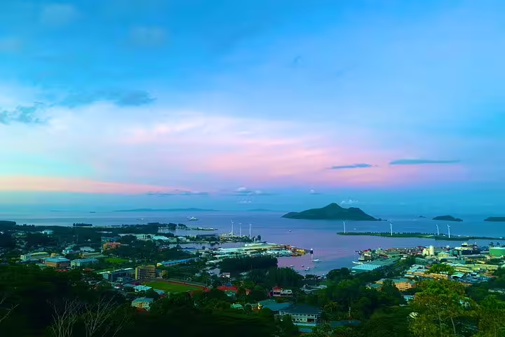Stunning panoramic view of Seychelles harbor at sunset with pastel skies and distant islands.