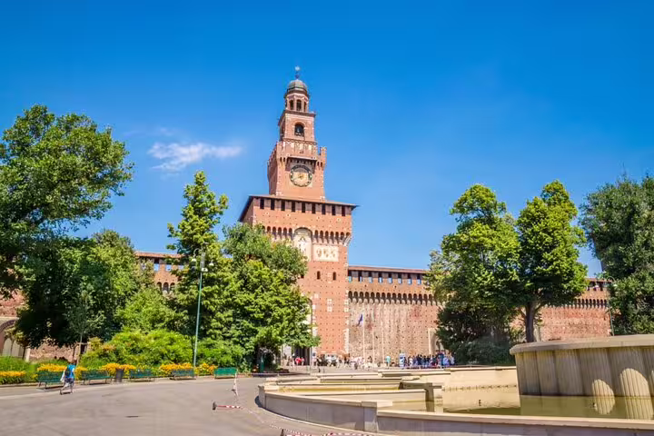 Sforza Castle main tower with clock, fountain in foreground, Milan Italy on sunny day