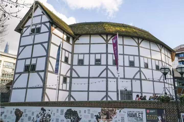 Shakespeare's Globe Theatre in London, a circular Tudor-style building with white walls and thatched roof