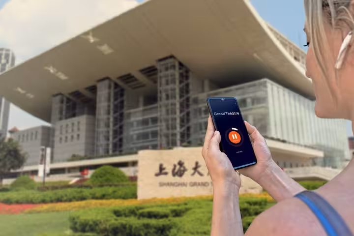 Tourist using audio guide app on smartphone in front of Shanghai Grand Theatre