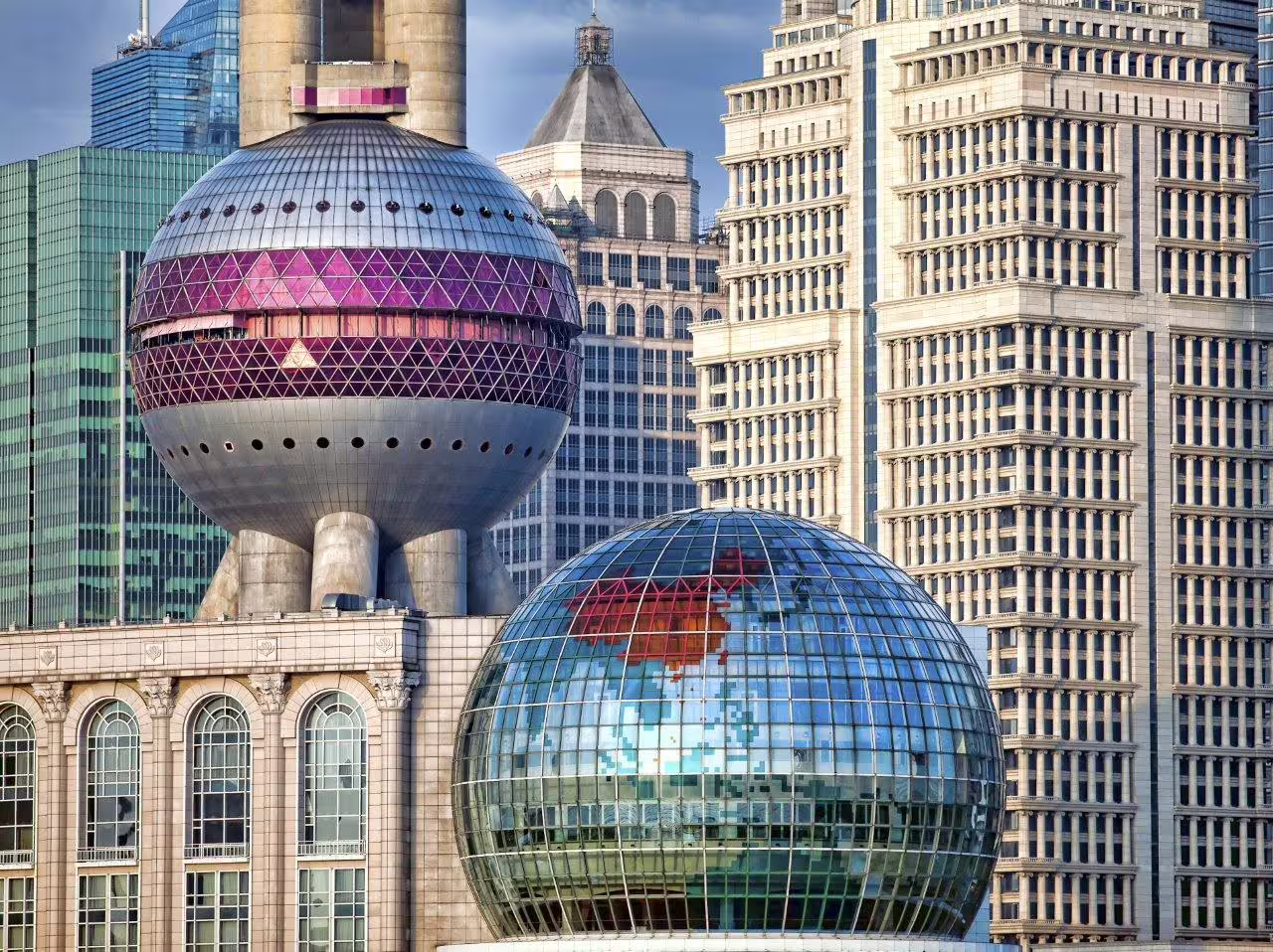 Shanghai cityscape featuring the futuristic Oriental Pearl Tower and modern skyscrapers on a sunny day.