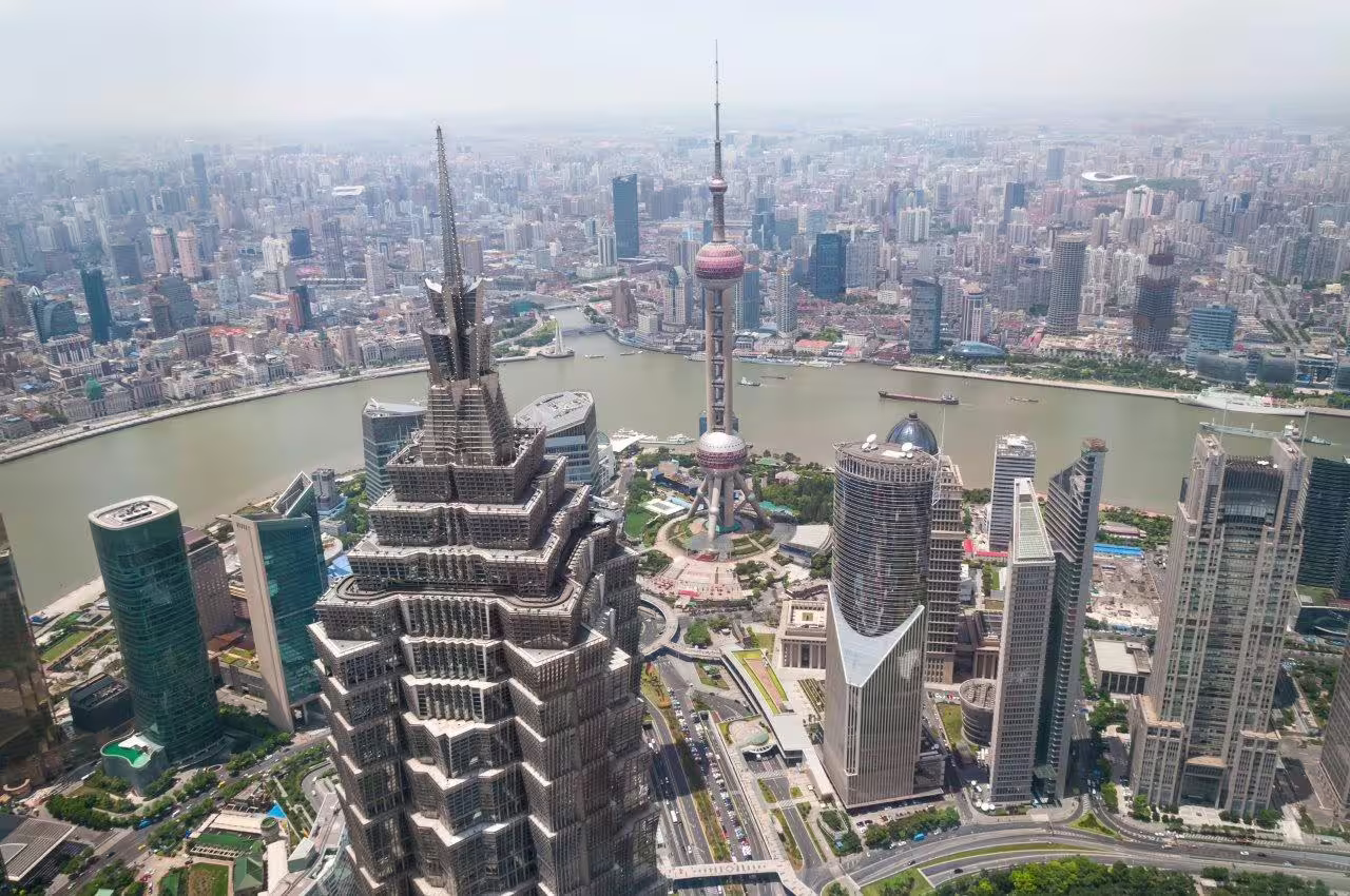 Aerial view of Shanghai skyline featuring the iconic Oriental Pearl Tower and modern skyscrapers along the Huangpu River.