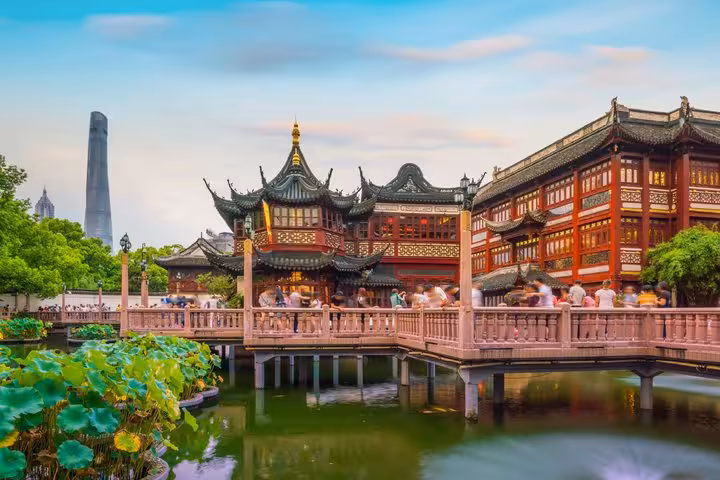 Yu Garden pagoda and zigzag bridge over lotus pond with Shanghai Tower in background