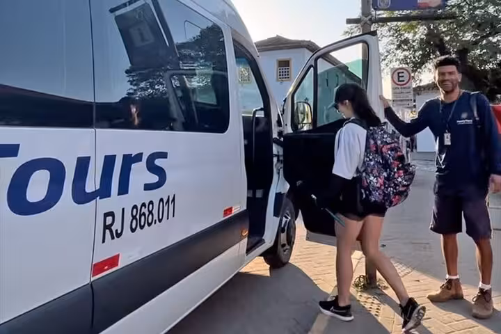 A traveler with a backpack getting onto a shared Paraty Tours van for a trip from Rio de Janeiro to Angra dos Reis.