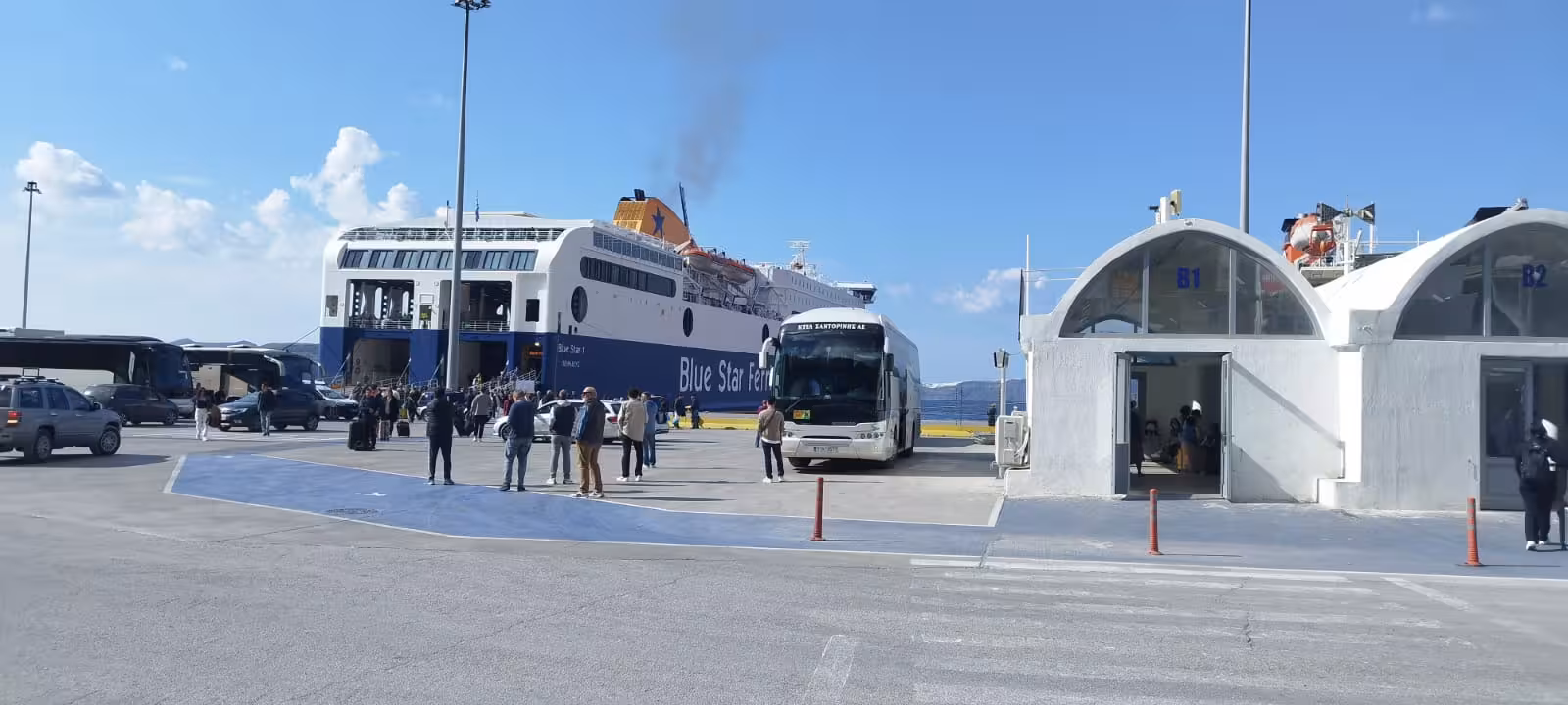 Shared transfer service pickup at ferry port with coach bus and passengers, easy island transport connection