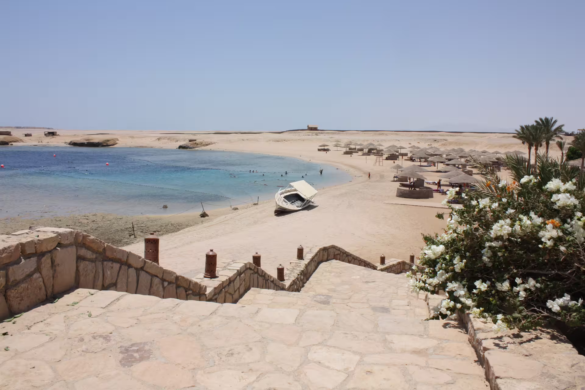 Sharm el Naga beach lagoon with turquoise Red Sea water, sandy shore, sun umbrellas and boat, Egypt
