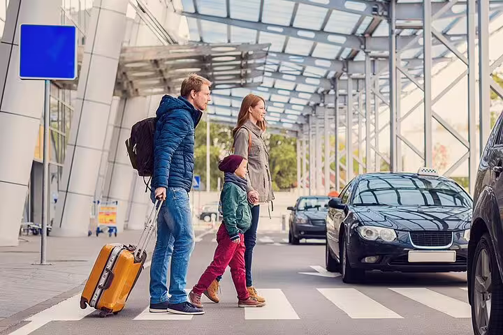 Family with luggage crossing to taxi for Sharm El Sheikh Airport private transfer pickup at terminal curbside
