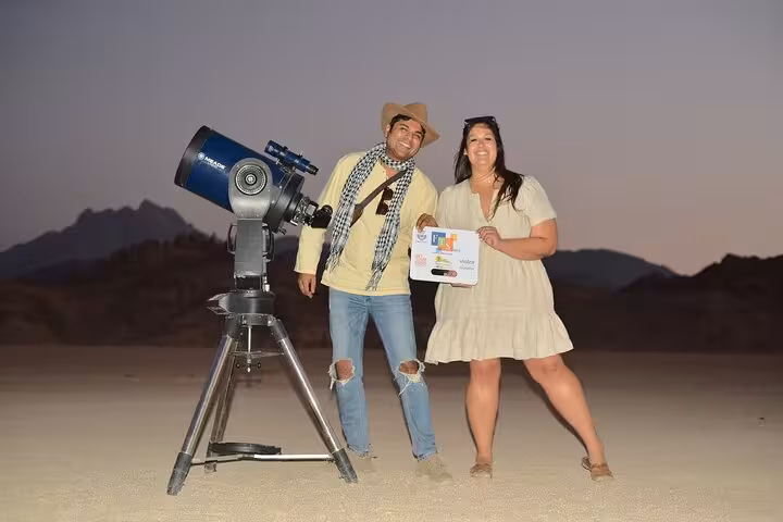Tour guests pose by desert telescope in Sharm El-Sheikh after ATV quad bike and camel ride with BBQ show