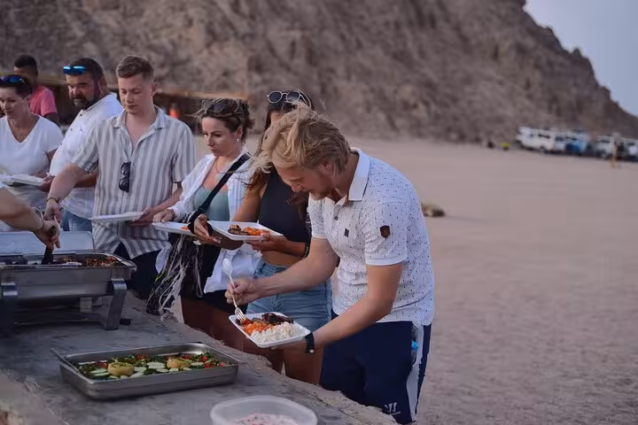 Guests serve themselves BBQ dinner at desert camp in Sharm El-Sheikh tour with show after camel ride