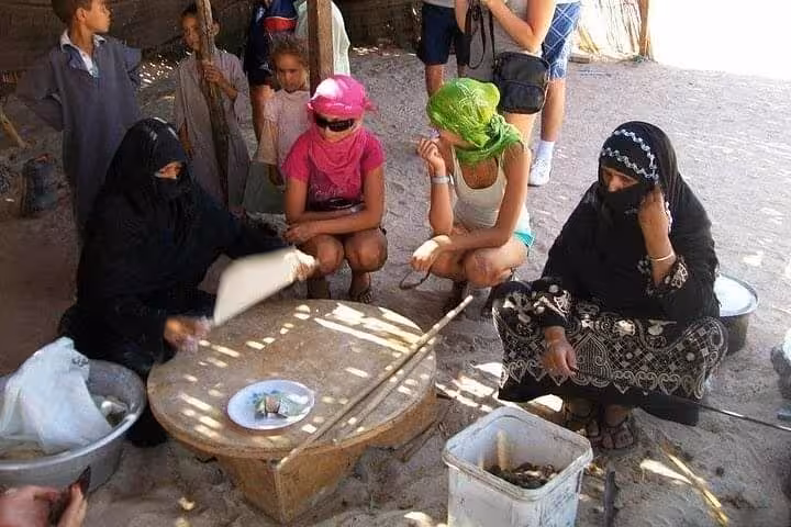 Tourists watch Bedouin bread baking during Sharm El Sheikh Bike Camel Canyon Tour cultural stop in Sinai