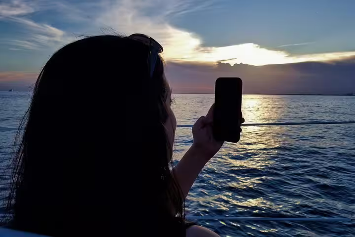Guest photographing Red Sea sunset from Sharm El Sheikh dinner cruise boat, relaxing evening sea views