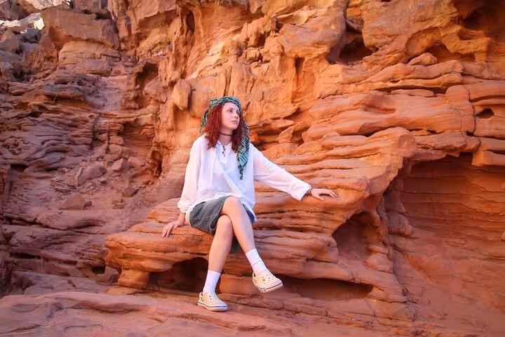 Tourist resting on red rock walls in Sinai Canyon during Sharm El-Sheikh jeep adventure to Dahab