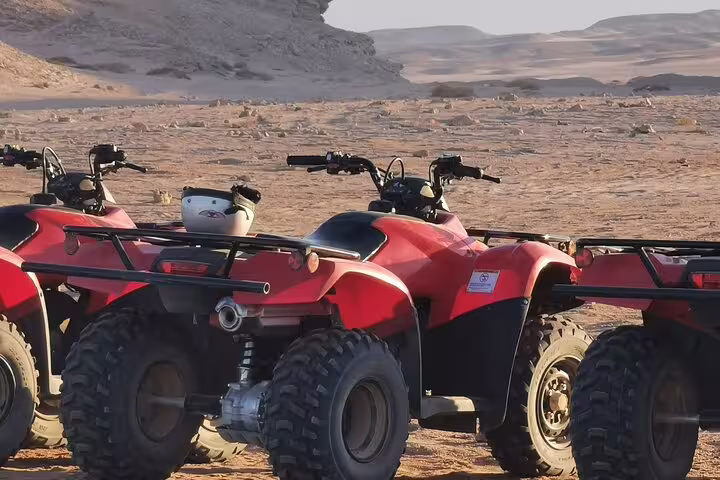 Red quad bikes parked in Sharm El Sheikh desert camp area, ATV safari experience with camel ride and Bedouin dinner