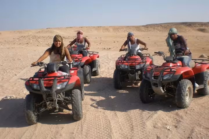 Group quad biking across the Sharm El Sheikh desert on a shared safari tour with ATV adventure experience