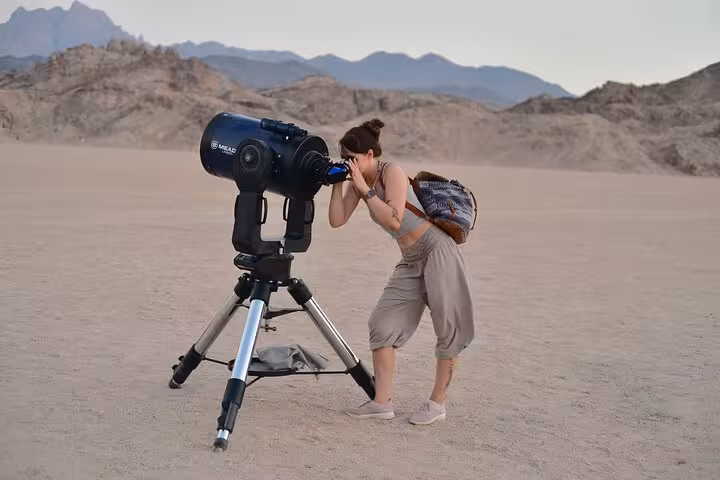 Guest using telescope for Sinai Desert stargazing in Sharm El-Sheikh, part of camel ride, BBQ dinner and show