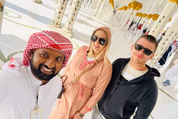 Visitors with guide inside Sheikh Zayed Grand Mosque colonnade on Abu Dhabi city tour with Qasr Al Watan entry
