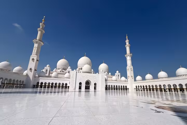 Majestic white domes and minarets of Sheikh Zayed Grand Mosque under clear blue sky Abu Dhabi tour