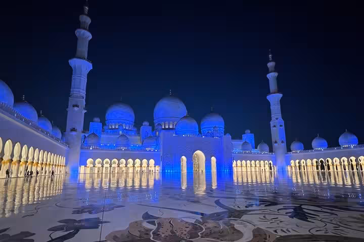 Sheikh Zayed Grand Mosque Abu Dhabi at night with blue lighting and reflections, private city tour entrance included