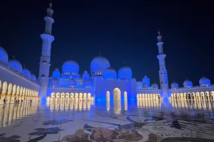 Sheikh Zayed Grand Mosque at night in Abu Dhabi, blue-lit domes and courtyard on sunset visit tour