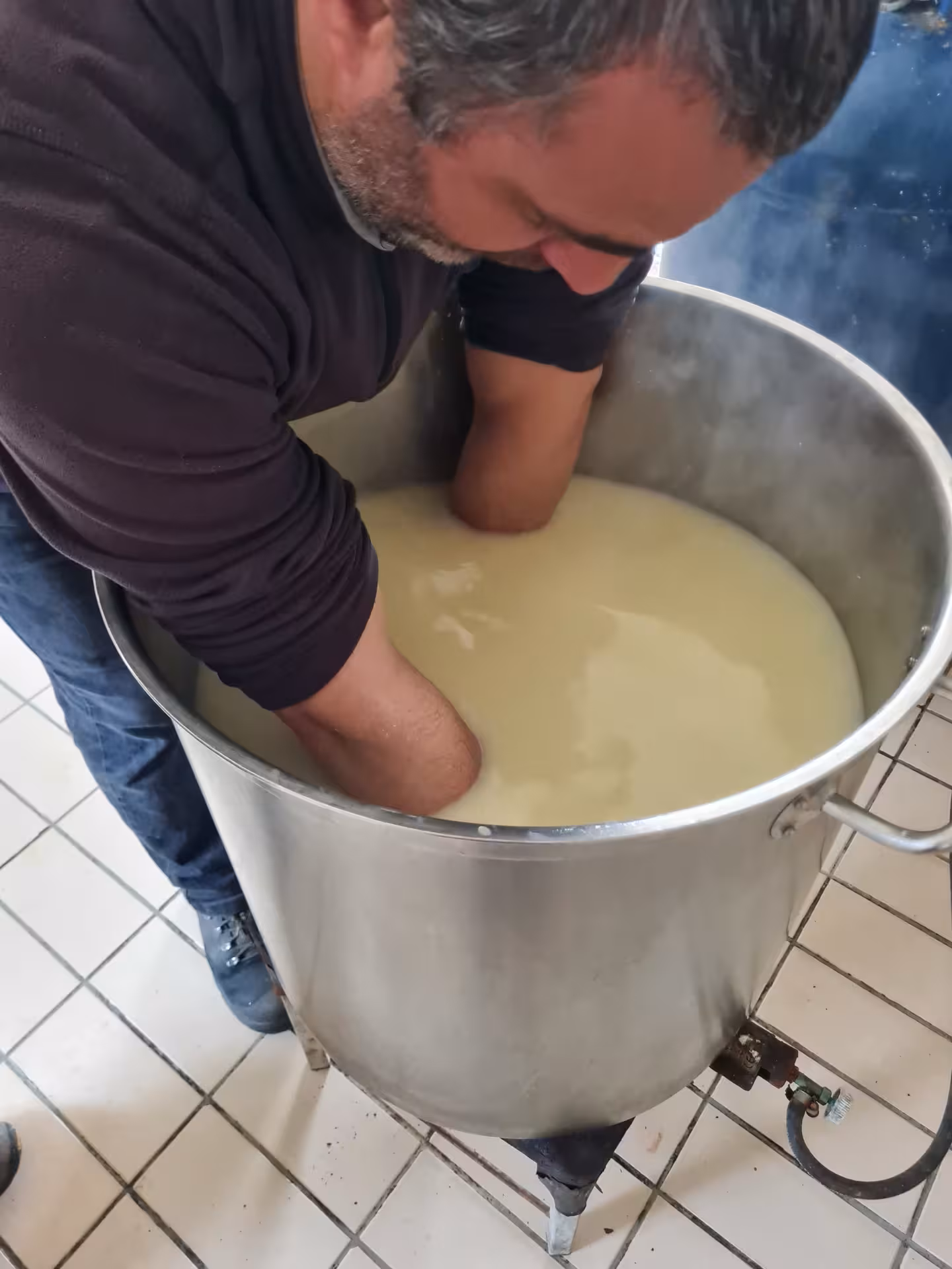 Shepherd stirring milk in a large pot, part of the Bitti Sardinian day tour showcasing traditional cheese-making techniques.