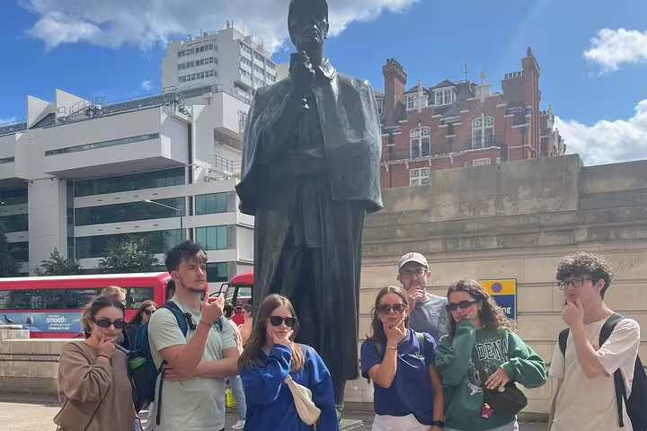 Tourists posing with Sherlock Holmes statue in London, mimicking his thinking pose