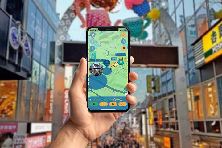 Hand holding a phone with an interactive tour map app while exploring Tokyo's vibrant Shibuya shopping street