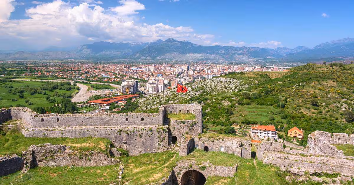Aerial view of Shkoder with historic fortress, lush greenery, and distant mountains, perfect for a cultural day trip.