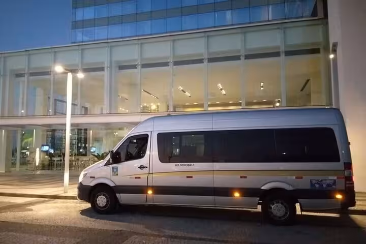 Modern shuttle parked in front of a glass building, ready for transport from Ilha Grande to Rio de Janeiro.