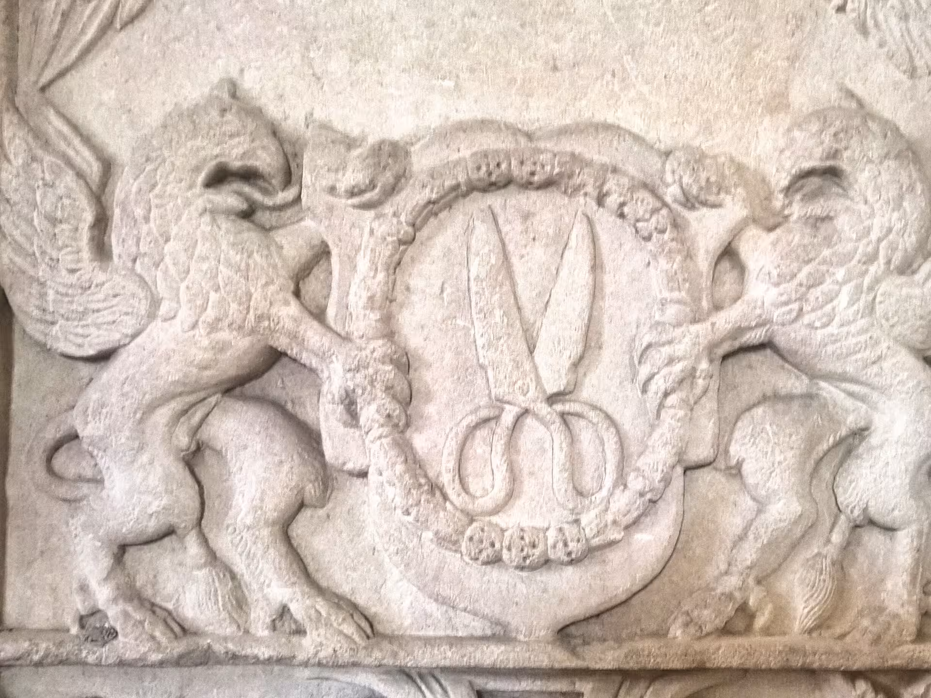 Stone relief carving of scissors coat of arms flanked by griffins in Sibiu castle