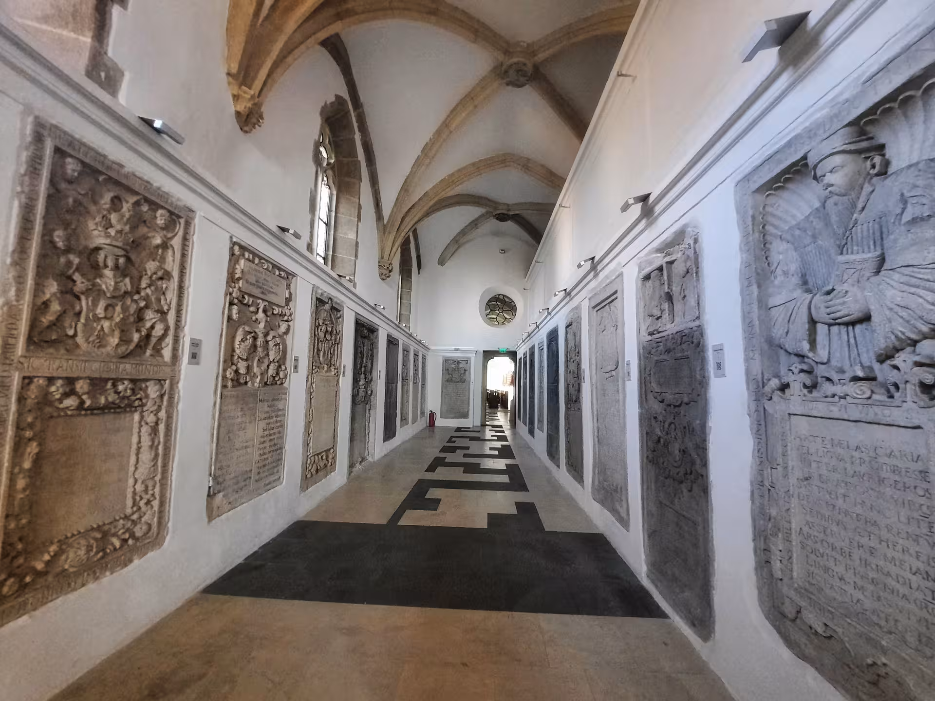 Gothic corridor with carved stone epitaphs and vaulted ceiling in Sibiu historic building
