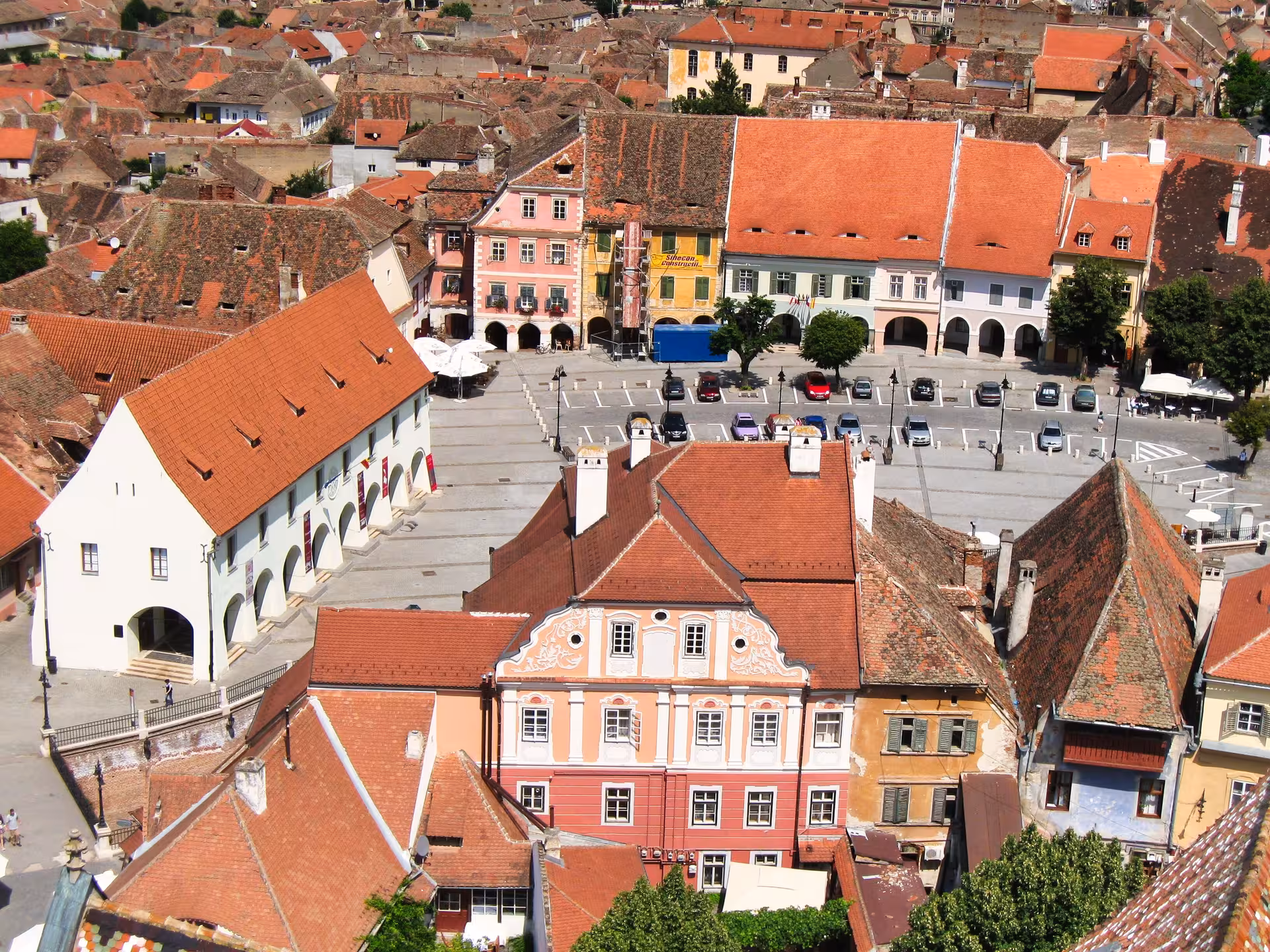 Aerial view of Sibiu's historic main square surrounded by colorful medieval buildings and terracotta rooftops