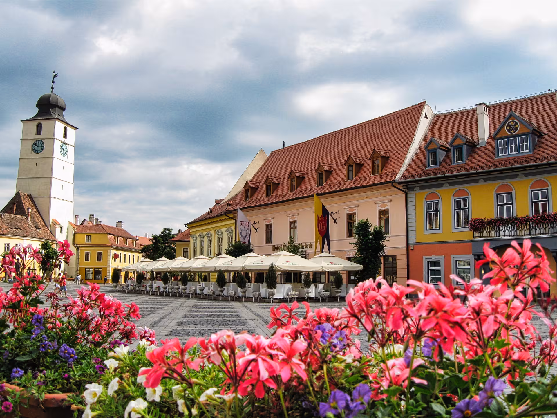 Colorful Sibiu Large Square with clock tower and blooming flowers on a scenic day trip from Cluj-Napoca Romania