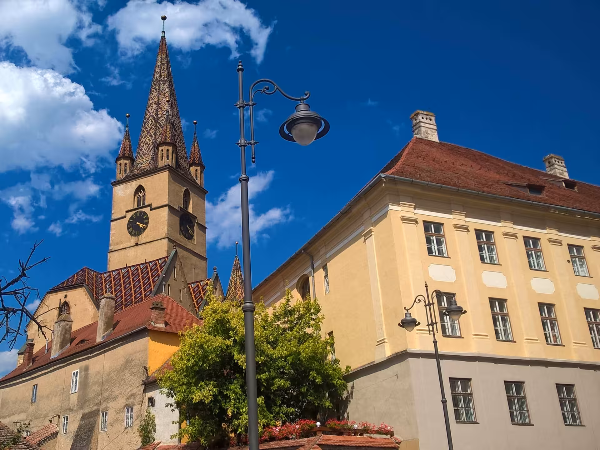 Lutheran Cathedral tower with colorful tiled spire and historic buildings in Sibiu, Romania
