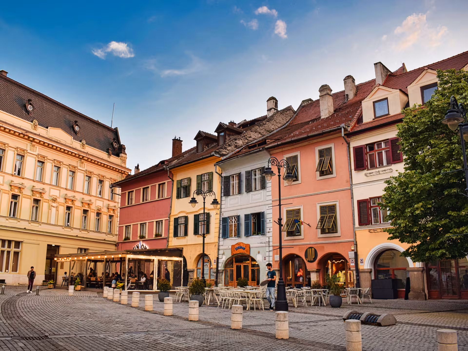 Colorful historic buildings and outdoor cafes in Sibiu old town square visited on a day trip from Cluj-Napoca