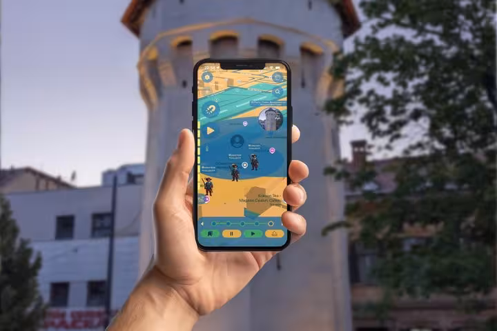 Hand holding smartphone displaying a self-guided walking tour app map in Sibiu with historical characters