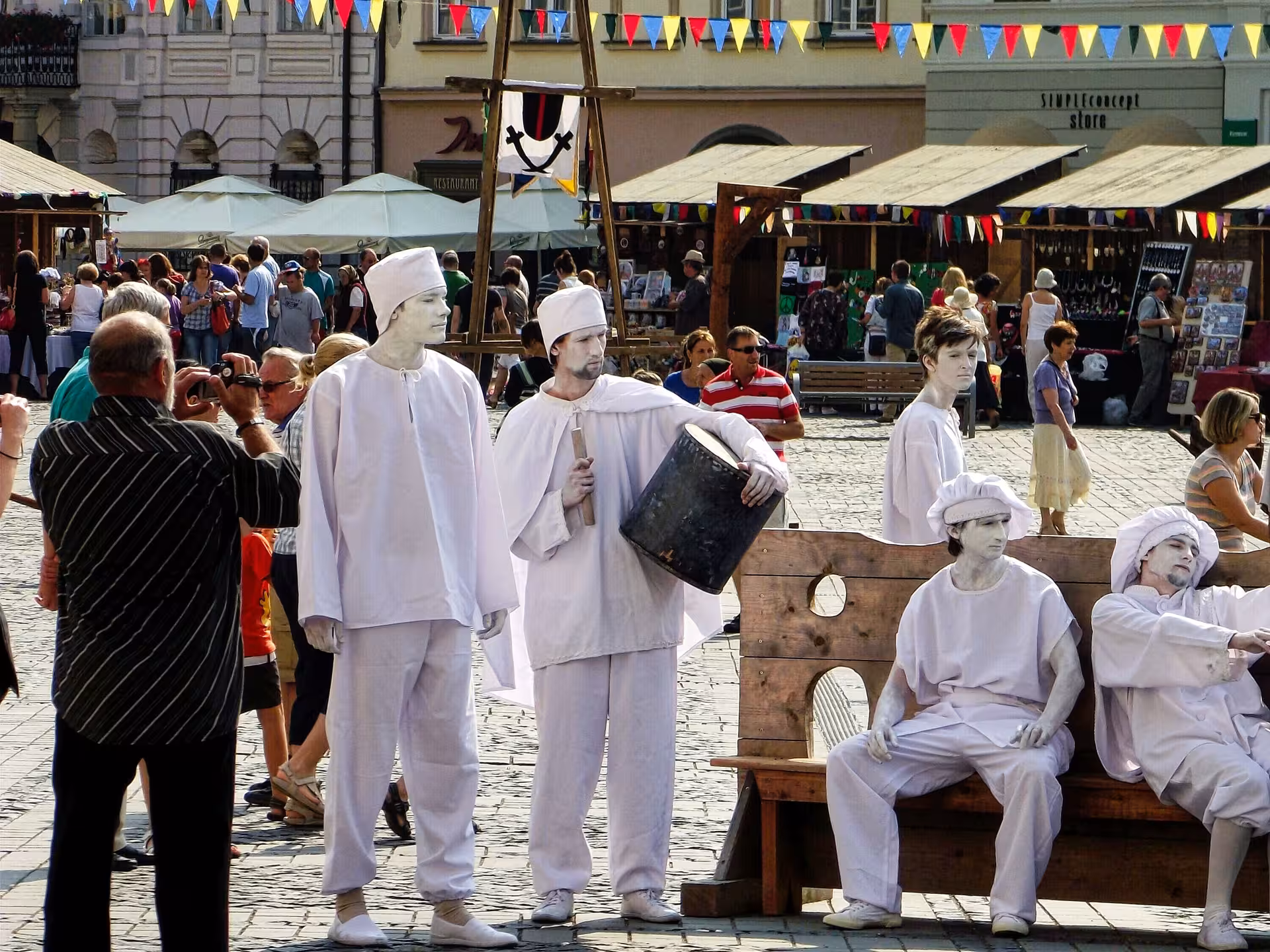 Street performers in white costumes entertaining tourists in Sibiu historic square on a Transylvania day trip