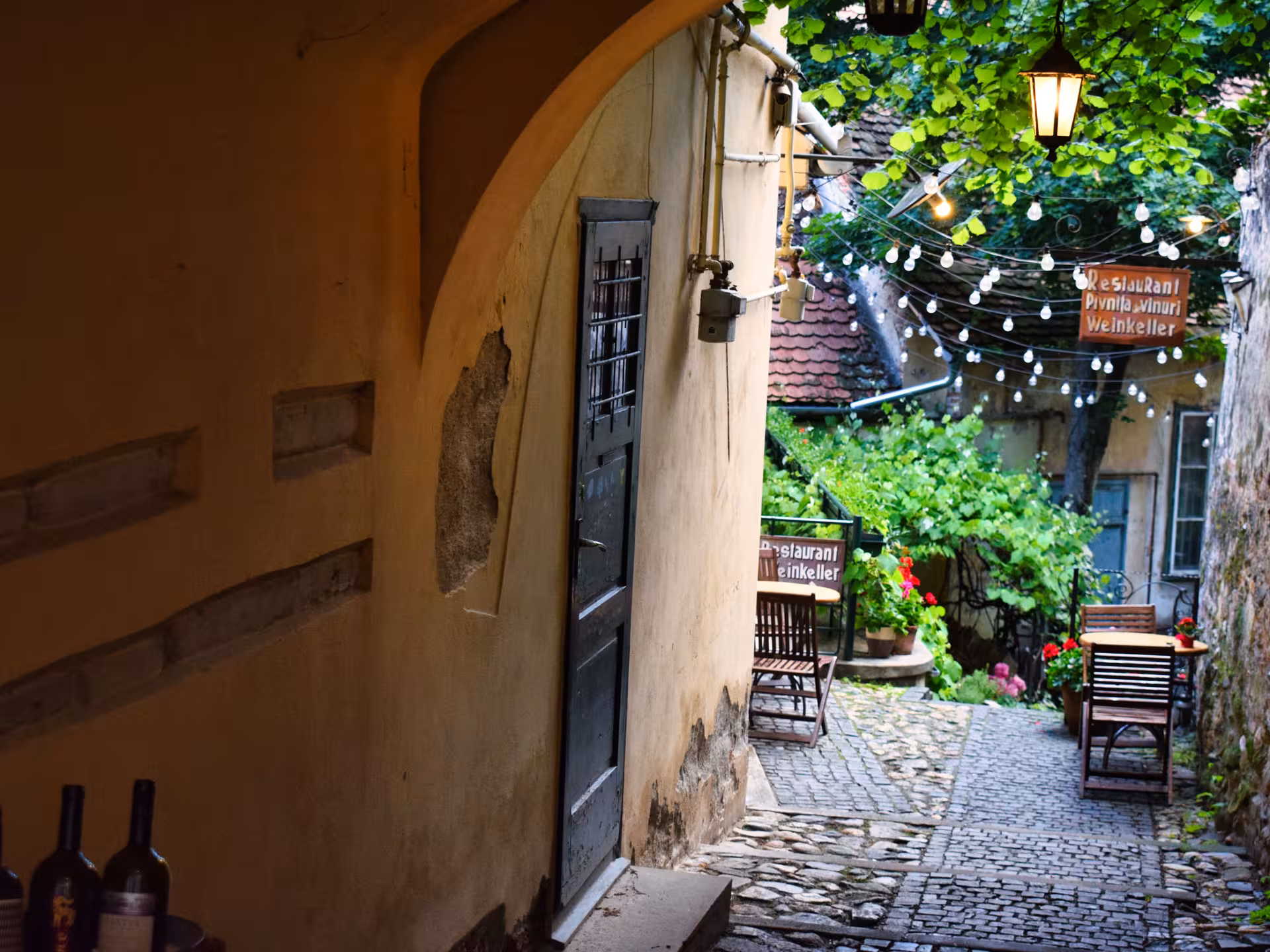 Charming cobblestone courtyard of a Sibiu wine cellar restaurant with string lights on a Cluj-Napoca day trip