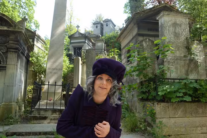 Female guide in purple coat and beret at Pere Lachaise Cemetery mausoleums, Paris