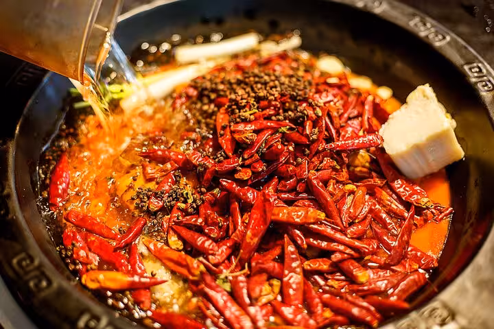 Traditional Sichuan hot pot with spicy red chilies and tofu, highlighting regional cuisine on Chengdu tour.
