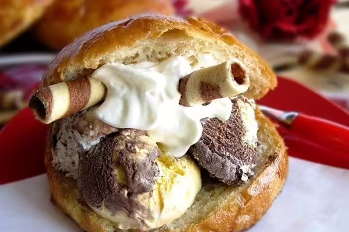 Traditional Sicilian brioche con gelato dessert with whipped cream, enjoyed on a Monreale and Mondello private tour from Palermo