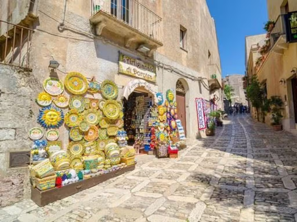 Colorful Sicilian ceramics displayed along a cobbled medieval street in Erice, visited on a private day trip from Palermo