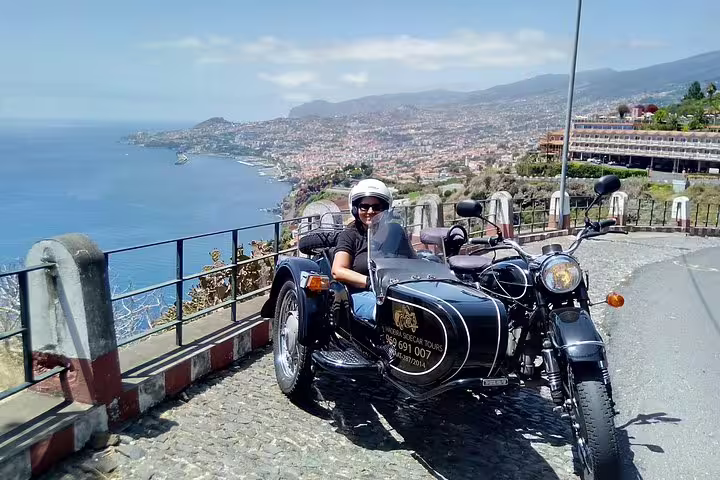 Person enjoying a scenic sidecar tour in Funchal with ocean and city views, perfect for a unique downtown adventure.