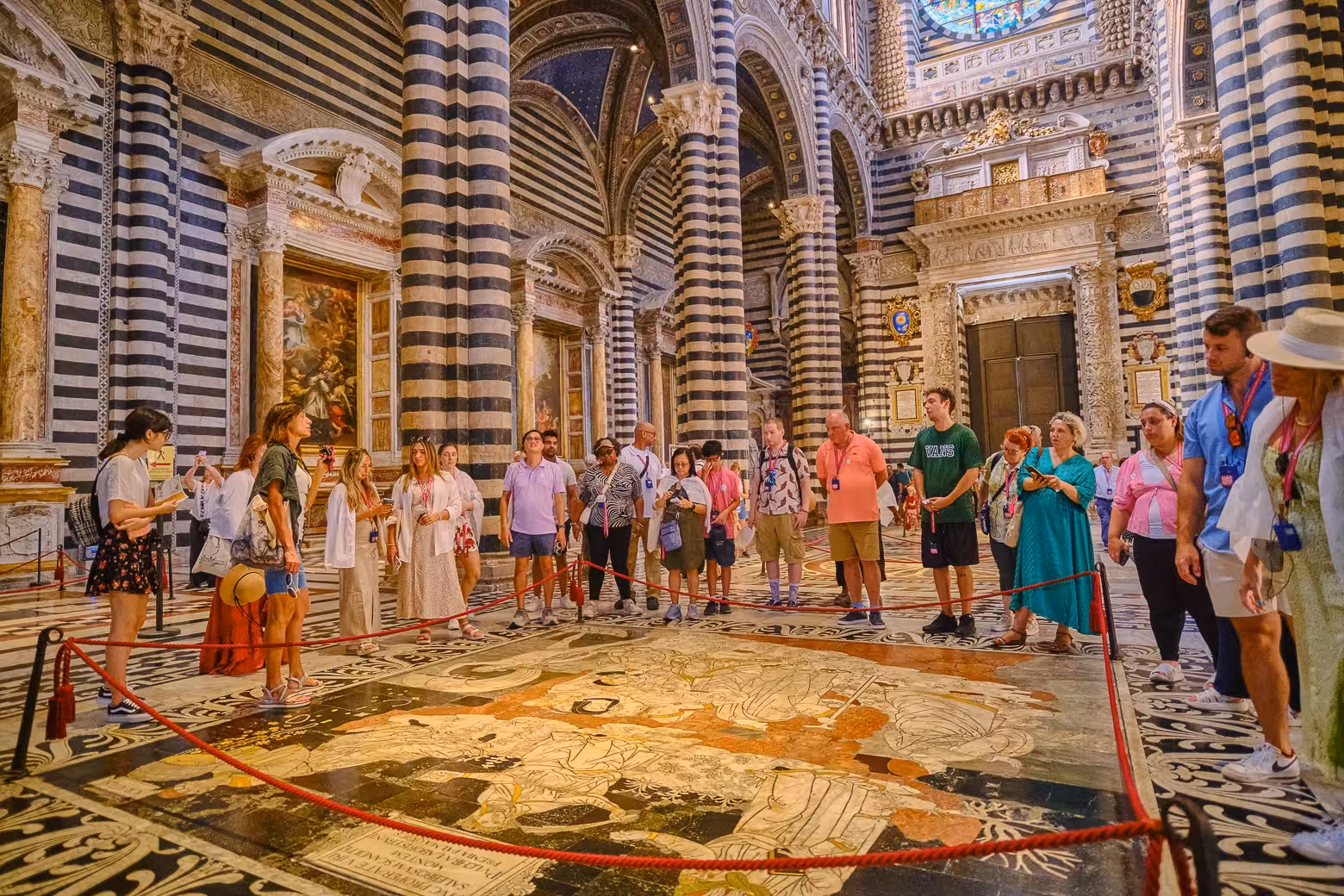 Visitors observing intricate floor mosaics inside Siena Cathedral during Tuscany tour.