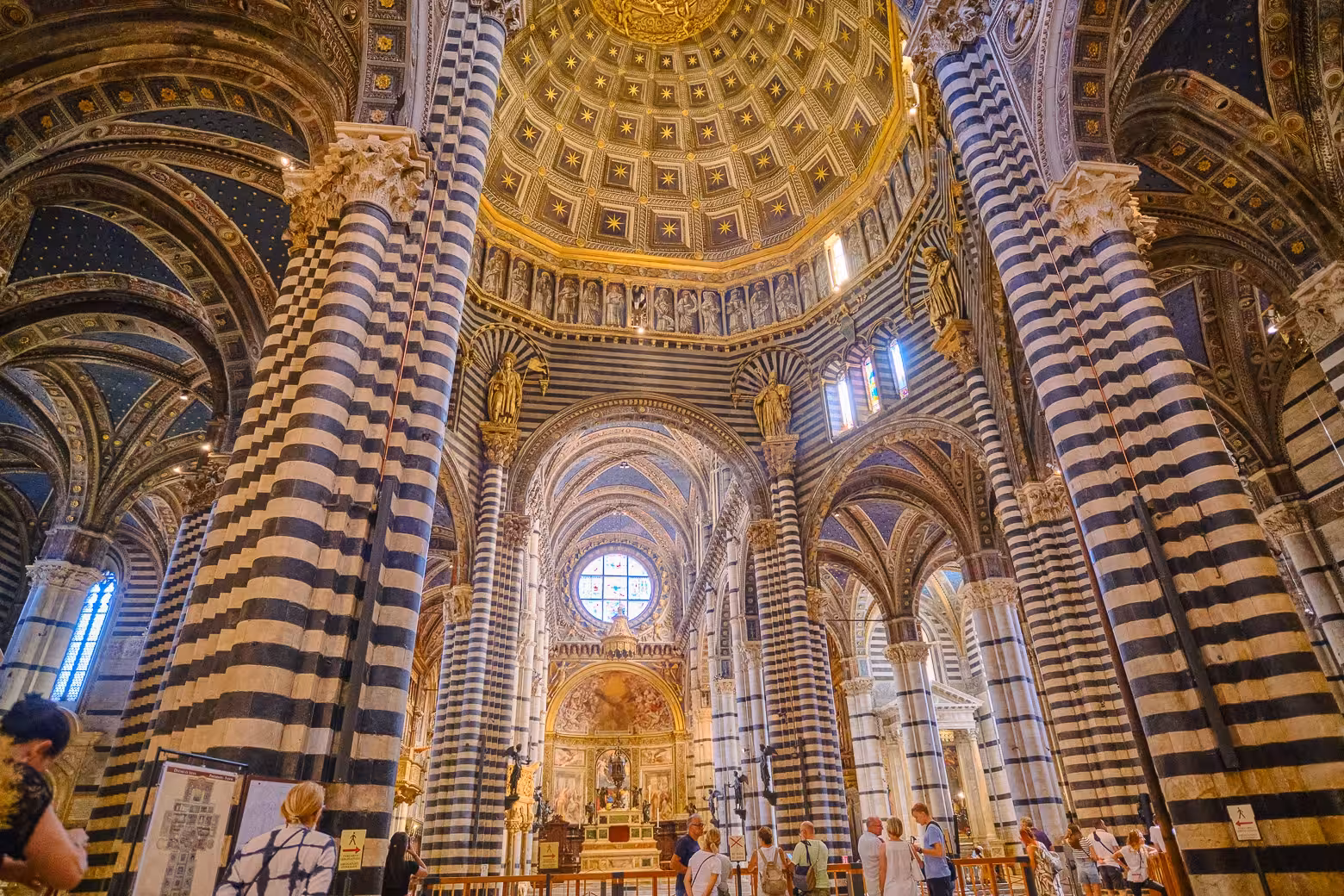 Visitors exploring the stunning striped interior of Siena Cathedral on a guided small-group tour from Florence.