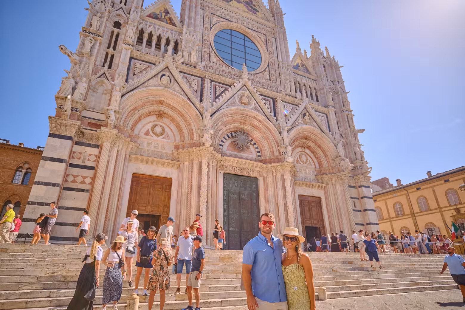 Tourists exploring the stunning facade of Siena Cathedral on a sunny day during Tuscany guided tour from Florence.