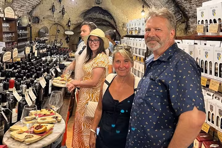 Tourists enjoying a wine tasting experience in a cozy cellar on the Siena, Cortona, Montepulciano tour.