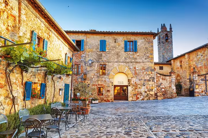 Charming courtyard in Siena with rustic stone buildings and outdoor seating, ideal for a Tuscany tour experience.