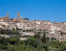 Panoramic view of Siena hilltop medieval town with terracotta rooftops and church towers under blue sky