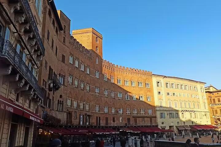 Sunlit Piazza del Campo in Siena with medieval brick palaces, cafés and crowds on a Tuscany wine and culture tour